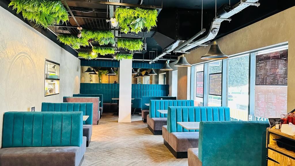 Inside Moe's Peri Peri: teal booths under hanging greenery